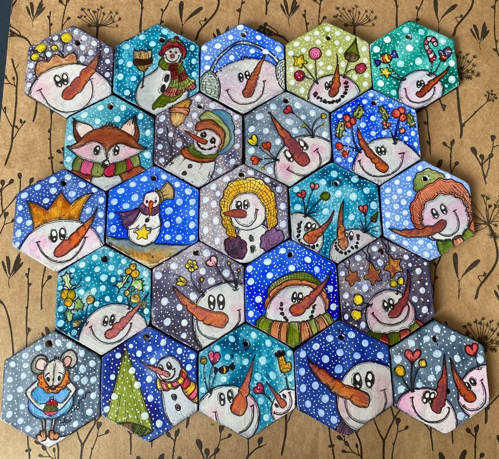 Colourful hand-painted hexagonal wooden winter ornaments with snowmen and winter characters.